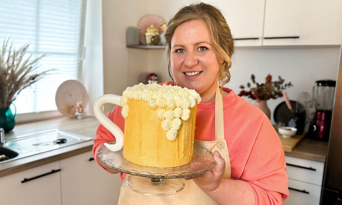 Rezepte & Inspirationen: Monika Nagl zeigt lächelnd ihre Bierkrug Torte zum Vatertag mit Dunkelbier und Butter von GOLDSTEIG.