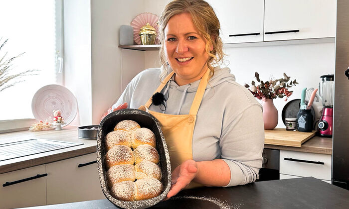 Rezepte & Inspirationen: Monika Nagl zeigt lächelnd ihr Hefegebäck Buchteln mit Nuss-Nougat-Creme und Butter von GOLDSTEIG.