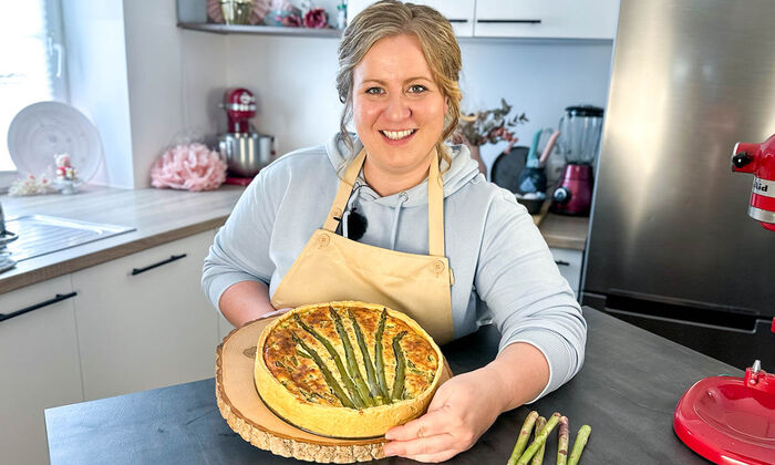 Rezepte & Inspirationen: Monika Nagl zeigt lächelnd ihre Spargelquiche mit Butter, Emmentaler und Ricotta von GOLDSTEIG.