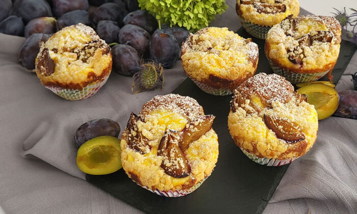 Rezepte & Inspirationen: Zwetschgen-Ricotta-Muffins mit Butter von GOLDSTEIG auf grauem Geschirrtuch.