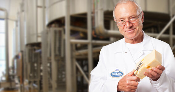 Mozzarella Käsefacts vom GOLDSTEIG Käsemeister - GOLDSTEIG Käsespezialitäten Käsemeister mit einem Stück Emmentaler in der GOLDSTEIG Käserei