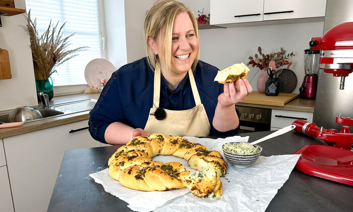Rezepte & Inspirationen: Monika Nagl zeigt lächelnd ihren Hefezopf mit Mozzarella und Kräuterbutter von GOLDSTEIG. 