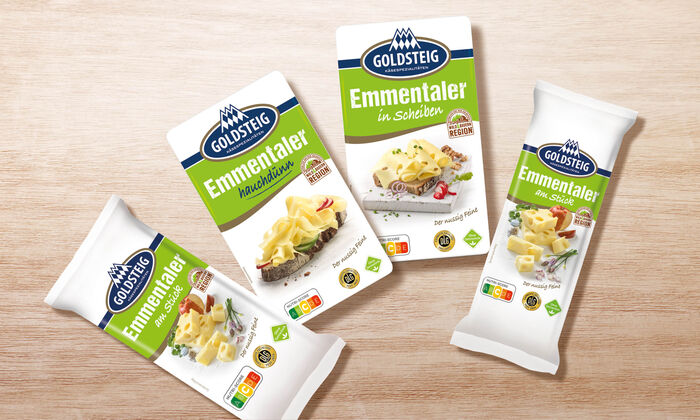 Emmentaler Sortiment von GOLDSTEIG auf Holztisch: Emmentaler hauchdünn, am Stück 250g, am Stück 400g und in Scheiben