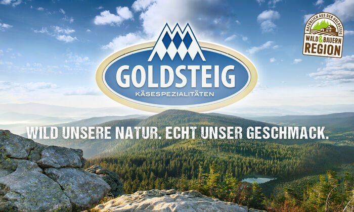 Goldsteig Käsespezialitäten Logo darunter Slogan, Bayerischer Wald im Hintergrund