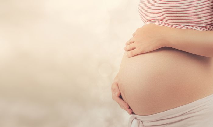 Schwangere Frau mit Händen auf dem Bauch