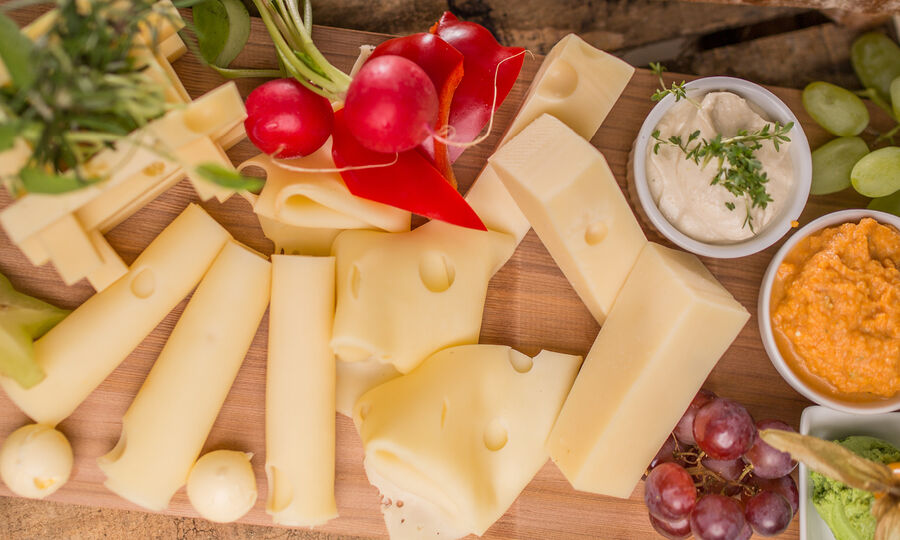 Käsebrett - GOLDSTEIG Käsespezialitäten Käsebrett von GOLDSTEIG mit Gemüse und Obst garniert