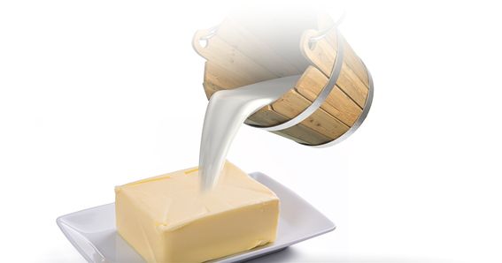 Altertümlicher Eimer der 5 Liter Milch in 250g Butter auf weißem Porzellan schüttet