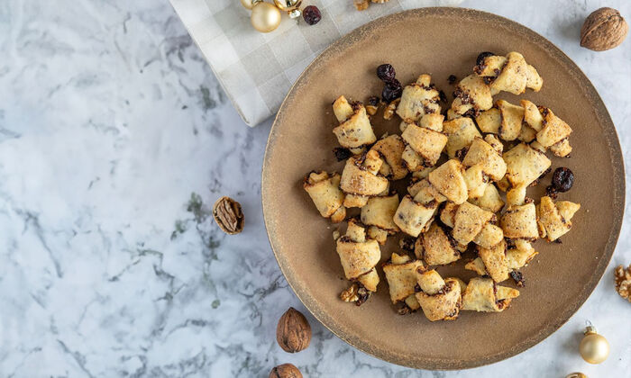 Rezepte & Inspirationen: Rugelach mit Cranberry-Nuss-Füllung (Butter, Ricotta) von GOLDSTEIG auf braunem Teller.