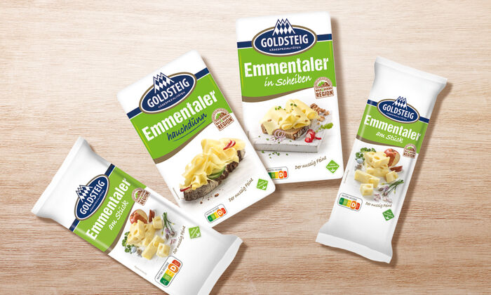 Emmentaler Sortiment von GOLDSTEIG auf Holztisch: Emmentaler hauchdünn, am Stück 200g, am Stück 400g und in Scheiben