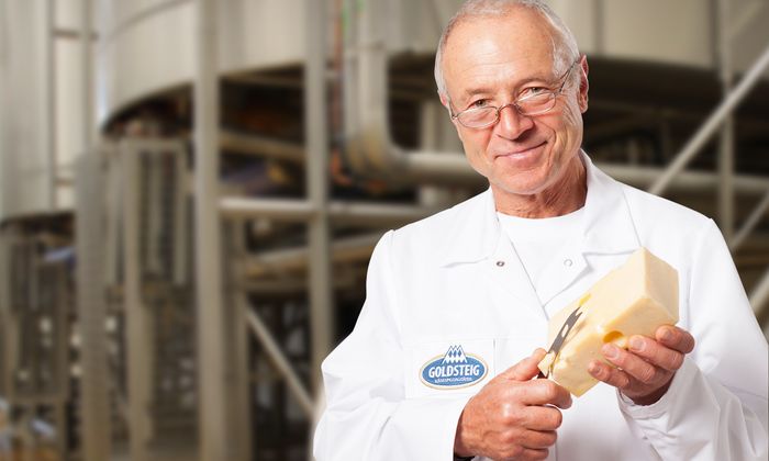 Mozzarella Käsefacts präsentiert vm GOLDSTEIG Käsemeister mit einem Stück Emmentaler in der Goldsteig Käserei