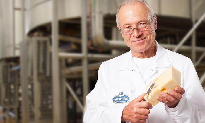 Mozzarella Käsefacts präsentiert vm GOLDSTEIG Käsemeister mit einem Stück Emmentaler in der Goldsteig Käserei