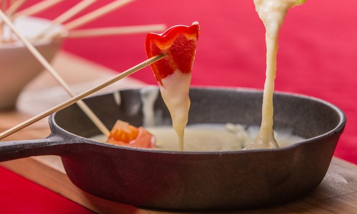 Käsefondue von GOLDSTEIG in Gusspfanne mit Gemüsestückchen auf Holzstäbchen