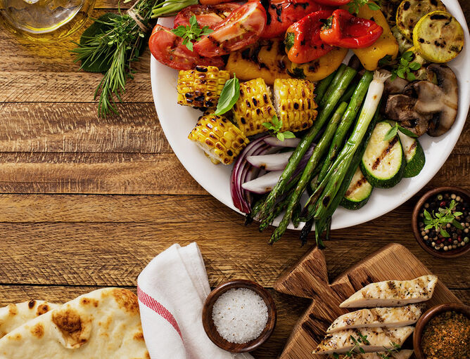 Maiskolben, Spargel, Paprika, Zucchini und Zwiebel in Teller auf Holztisch