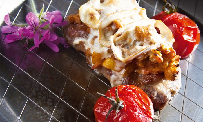 Limburger Rezept Schweinesteak in Brotsauce mit Mascarpone von GOLDSTEIG mit Brotwürfel, gebackenen Tomaten, Kräuter und würzigem Limburger von GOLDSTEIG überbacken auf Teller