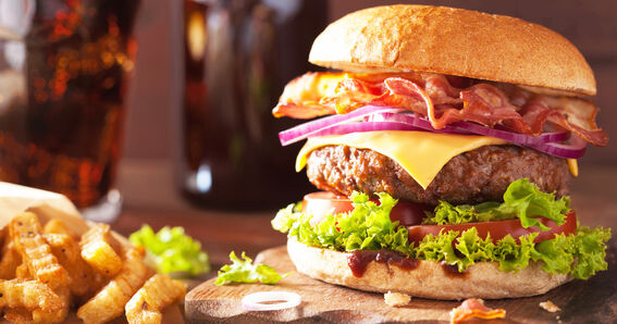 GOLDSTEIG als Arbeitgeber: Leckerer Bacon-Burger mit Pommes Frites auf Holzbrett serviert 