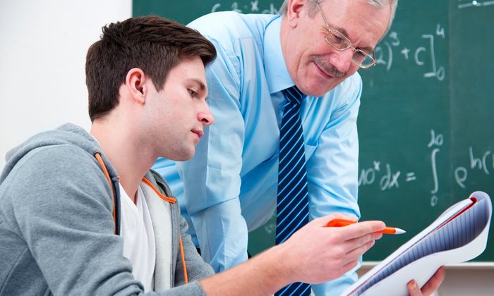 Schüler: Schüler lässt sich im Klassenzimmer von seinem Lehrer etwas erklären
