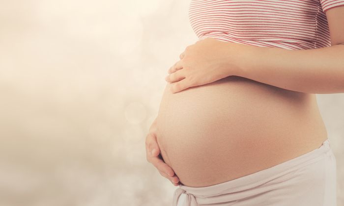 Schwangere Frau mit Händen auf dem Bauch