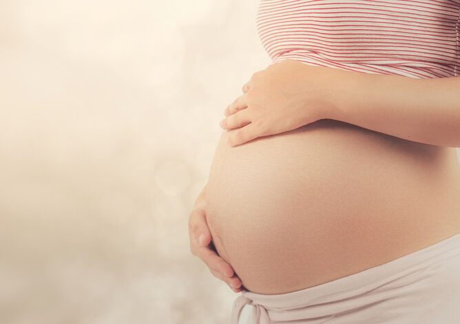 Schwangere Frau mit Händen auf dem Bauch