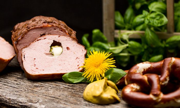 Mozzarella Rezept: Leberkäse gefüllt mit Bambini Mozzarella Mini von GOLDSTEIG auf Holzbrett mit Breze, Senf und Löwenzahn
