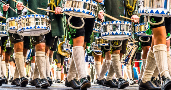 GOLDSTEIG als Arbeitgeber: Musikanten marschieren in bayerischer Tracht und spielen auf ihren Marschtrommeln