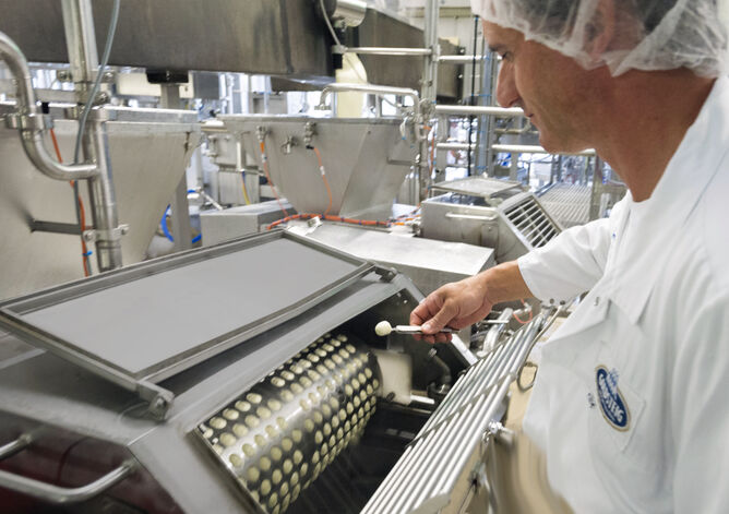 Ausbildung: Milchtechnologe prüft Produktion eines Mozzarella Minis in der Mozzarella Formmaschine