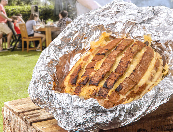 Aktionen und Neues: Grillbrot Käse - GOLDSTEIG Käsespezialitäten gegrilltes Brot mt Käse von GOLDSTEIG in Alufolie auf Holzkiste im Garten mit Grillgesellschaft