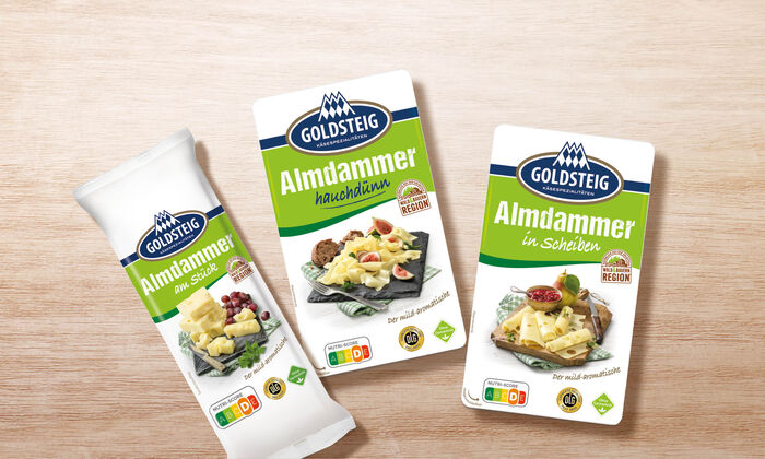 Almdammer Sortiment von GOLDSTEIG auf Holztisch: Almdammer hauchdünn, in Scheiben und am Stück