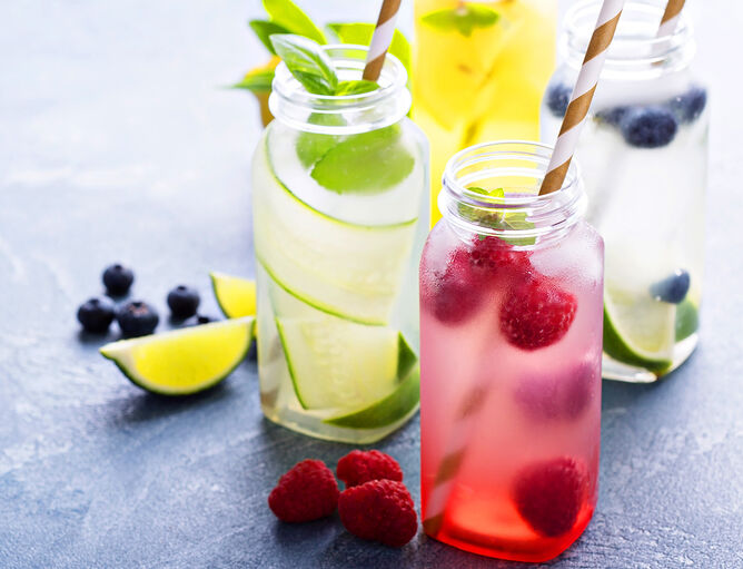 Selbstgemachte Limonade in den Geschmacksrichtungen Limette und Himbeere in Gläsern und mit frischen Früchten garniert