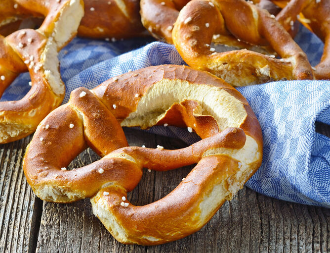 Brotzeit im Biergarten: Brezen auf blau-weißem Geschirrtuch und Holztisch 