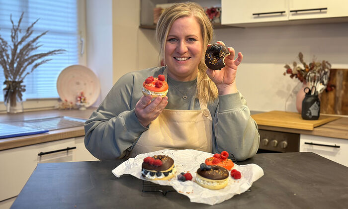 Rezepte & Inspirationen: Monika Nagl zeigt lächelnd ihre Fasching Donuts ohne Frittieren mit Mascarpone und Butter. Die Donuts sind mit Beeren und Streuseln dekoriert.