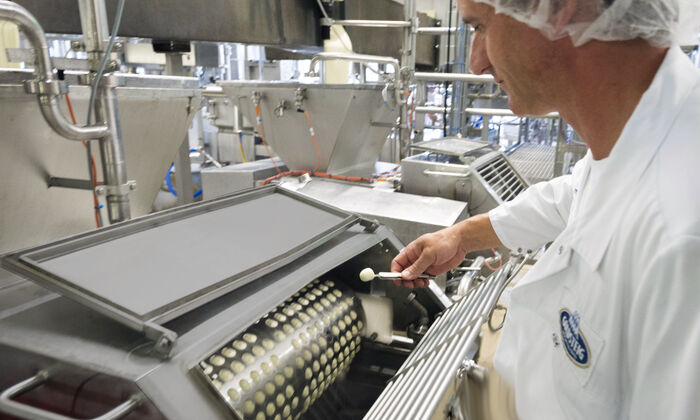 Ausbildung Milchtechnologe / Milchtechnologin: Milchtechnologe prüft Produktion eines Mozzarella Minis in der Mozzarella Formmaschine