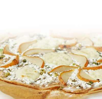 Protinella Rezept Birne-Protinella Flammkuchen mit körnigem Frischkäse und Frühlingsziebel von GOLDSTEIG auf Backpapier