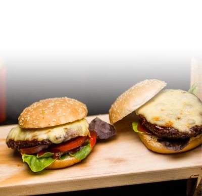 Emmentaler Rezept Klassischer Cheeseburger mit Emmentaler von GOLDSTEIG, Hackfleisch, Salat und Tomate auf Holzbrett 