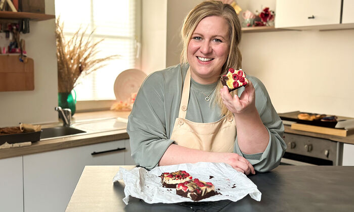 Rezepte & Inspirationen: Monika Nagl zeigt lächelnd ihre Himbeer Cheesecake Brownies mit Mascarpone und Butter von GOLDSTEIG.