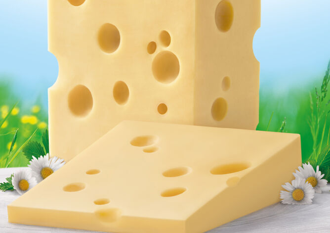 Tipp: Schneiden Sie die Rinde ab - GOLDSTEIG Käsespezialitäten Emmentaler Stück von GOLDSTEIG ohne Rinde mit Gänseblümchen vor Blumenwiese