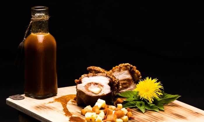 Emmentaler Rezept Mit Tramezzini und Emmentaler von GOLDSTEIG gefüllter Schweinebauch an Kartoffelwürfel und Löwenzahn auf Holzplatte