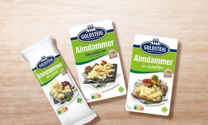 Almdammer Sortiment von GOLDSTEIG auf Holztisch: Almdammer hauchdünn, in Scheiben und am Stück