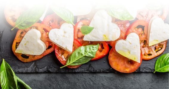 Tomatenscheiben mit herzförmigen Mozzarella von GOLDSTEIG und Basilikum belegt