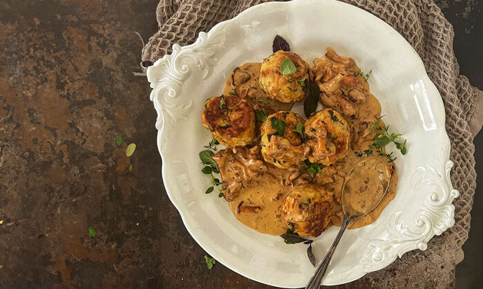 Rezepte & Inspirationen: Ricotta-Kräuterknödel mit Pfifferlingen und Butter von GOLDSTEIG auf weißem Teller.